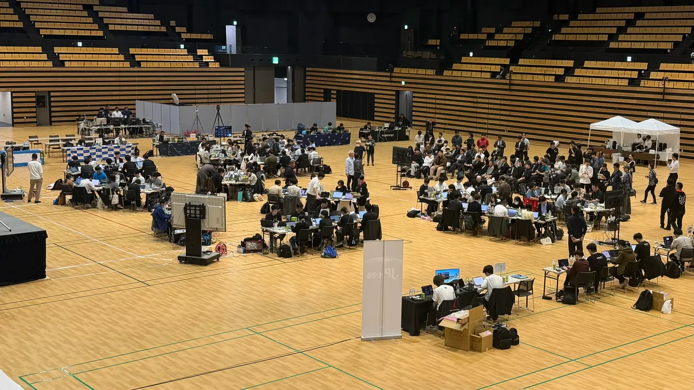 The competition floor at Hardening 2026 Agentic Collapse, rows of teams working at laptops across the arena.